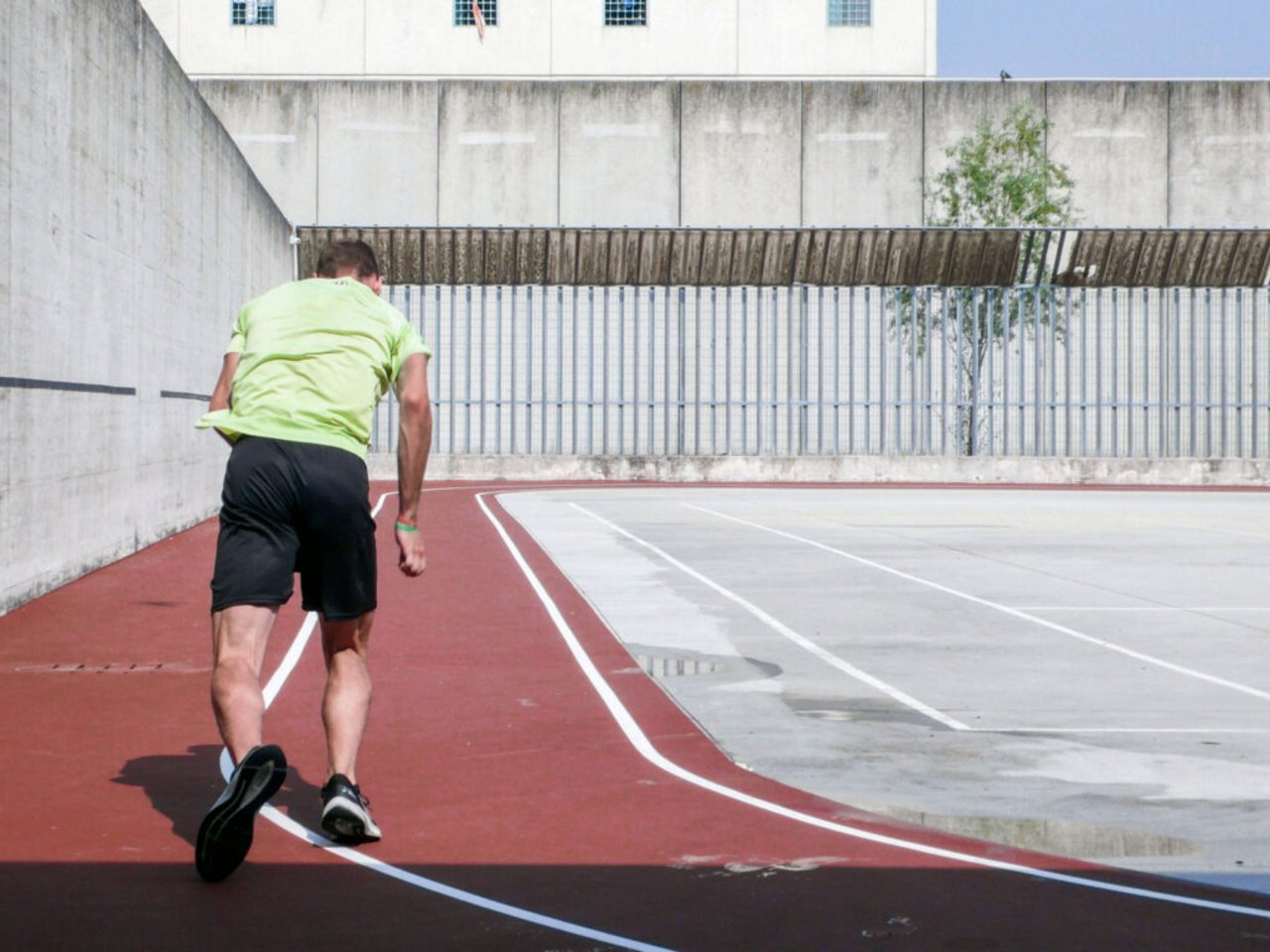 Un uomo corre su una pista d'atletica nel carcere di Bollate, in riferimento al progetto su sport e carcere
