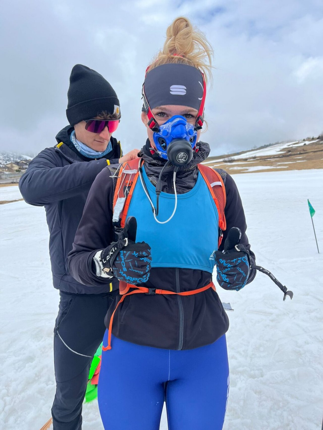 "Metabolimetro": raffigura la maschera che gli atleti indossano per misurare il consumo di ossigeno, la produzione di anidride carbonica, la frequenza respiratoria e i parametri derivati. La pettorina azzurra contiene un sensore inerziale per la misura di parametri cinematici e un GPS per la stima della posizione e del dislivello percorso. 